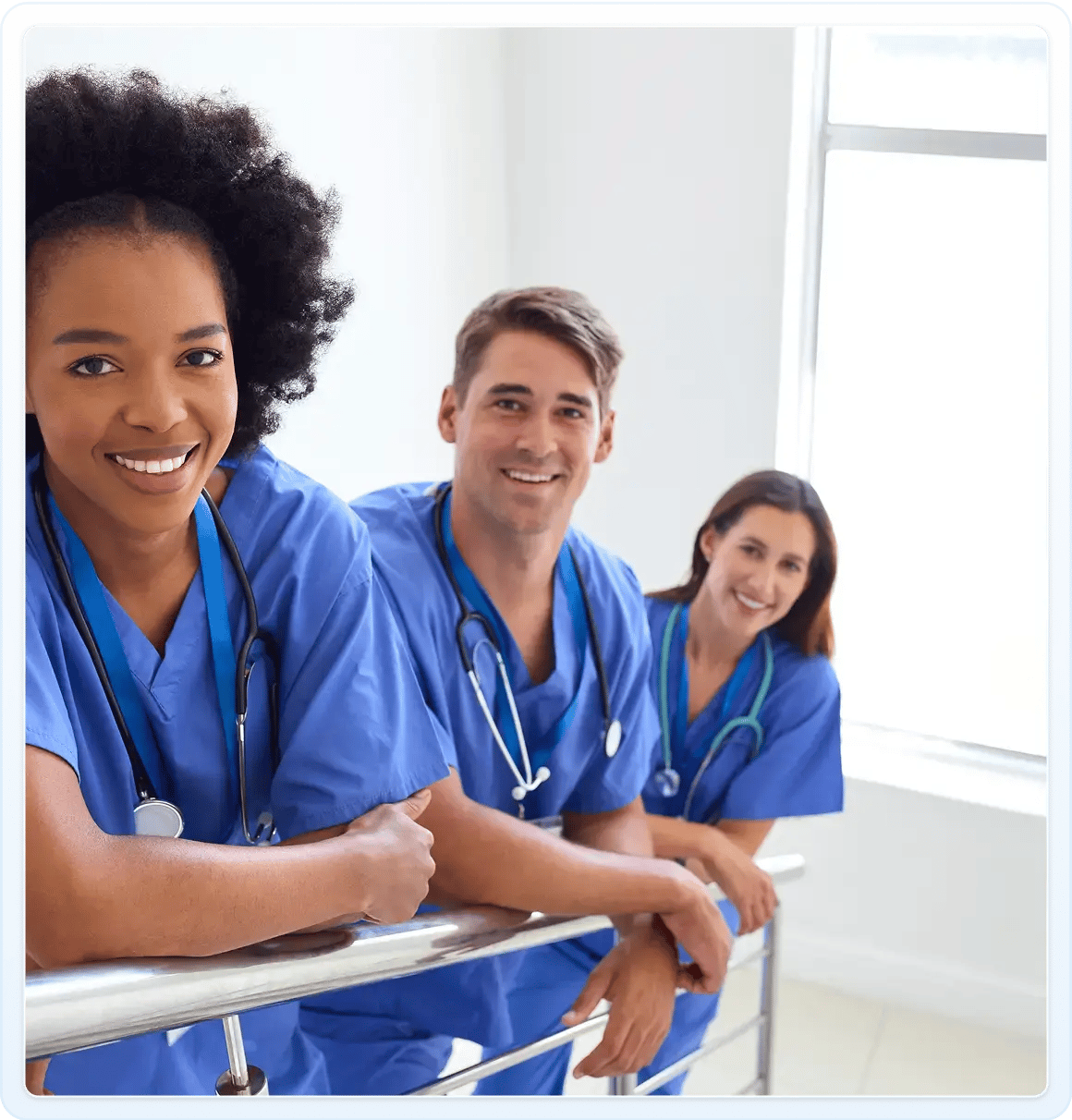 Three medical professionals wearing stethoscopes and smiling